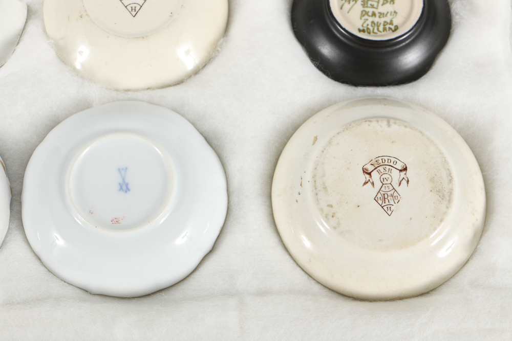 Twelve Porcelain Butter Pats In Glass Top Display Case