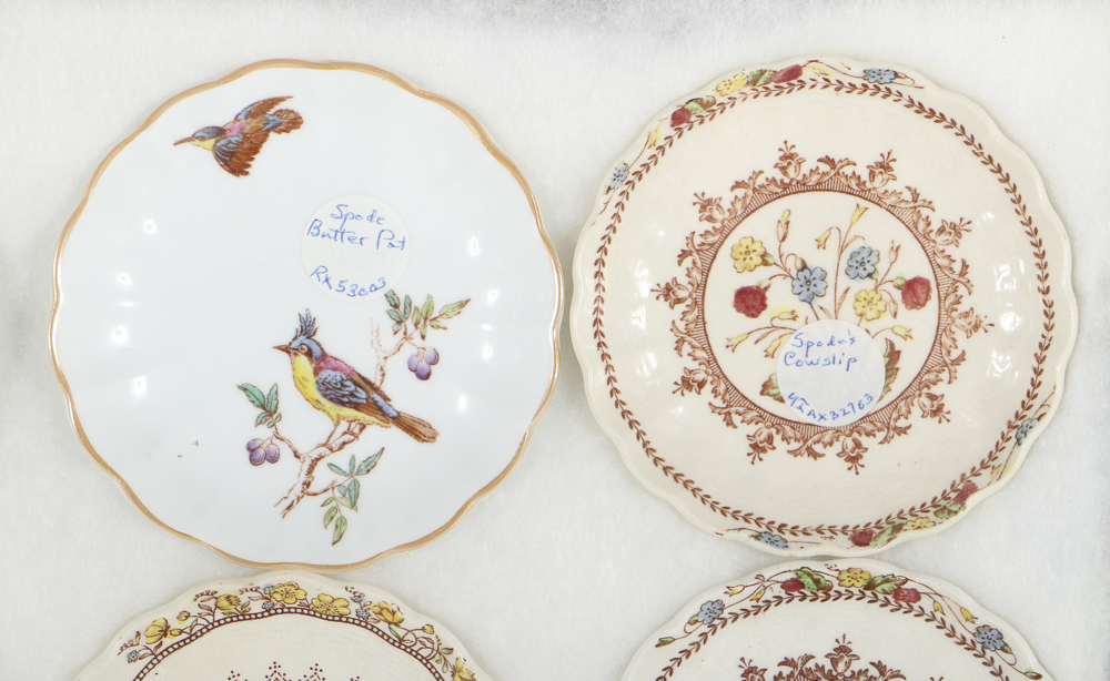 Twelve Porcelain Butter Pats In Glass Top Display Case