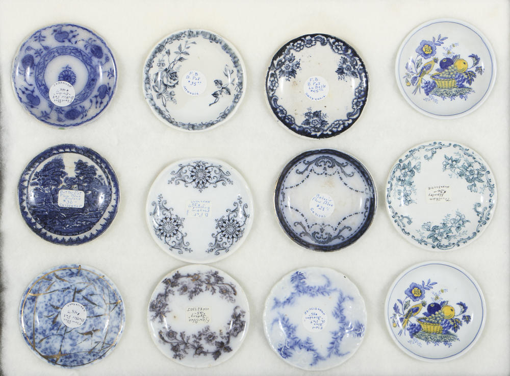 Twelve Porcelain Butter Pats In Glass Top Display Case