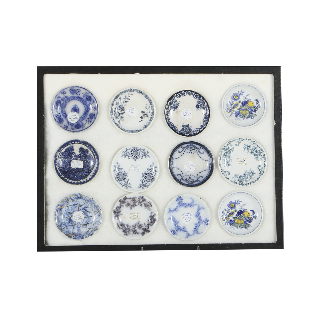 Twelve Porcelain Butter Pats In Glass Top Display Case