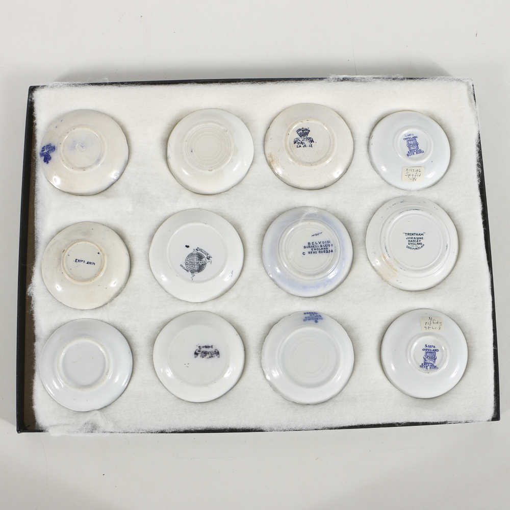 Twelve Porcelain Butter Pats In Glass Top Display Case