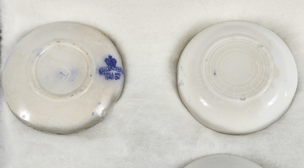 Twelve Porcelain Butter Pats In Glass Top Display Case