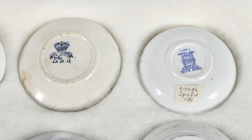 Twelve Porcelain Butter Pats In Glass Top Display Case