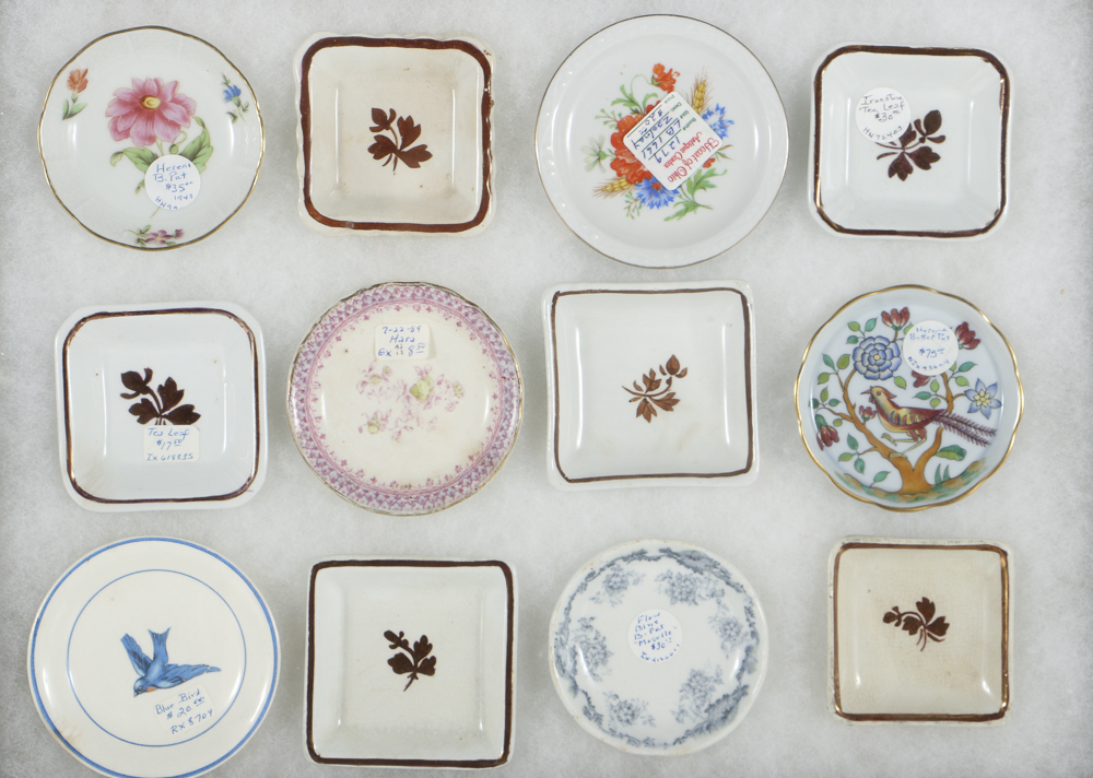 Twelve Porcelain Butter Pats In Glass Top Display Case