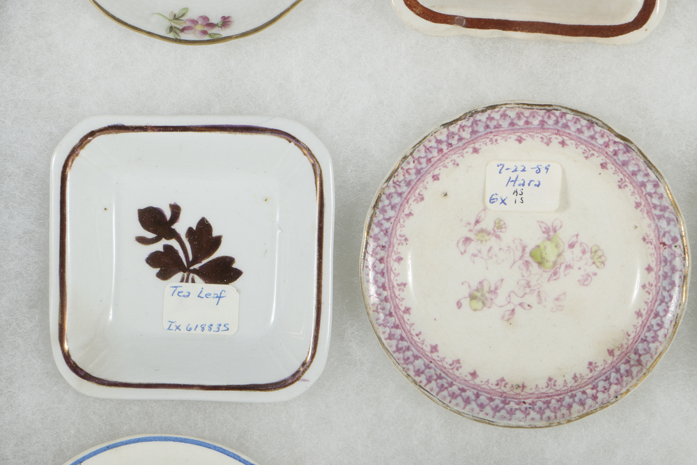 Twelve Porcelain Butter Pats In Glass Top Display Case