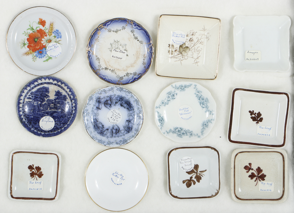 Twelve Porcelain Butter Pats In Glass Top Display Case