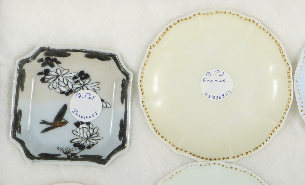 Twelve Porcelain Butter Pats In Glass Top Display Case