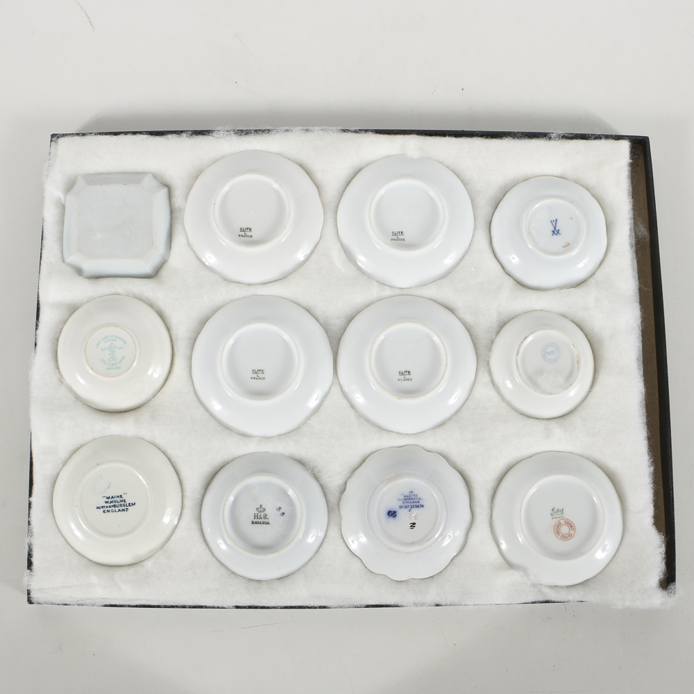 Twelve Porcelain Butter Pats In Glass Top Display Case