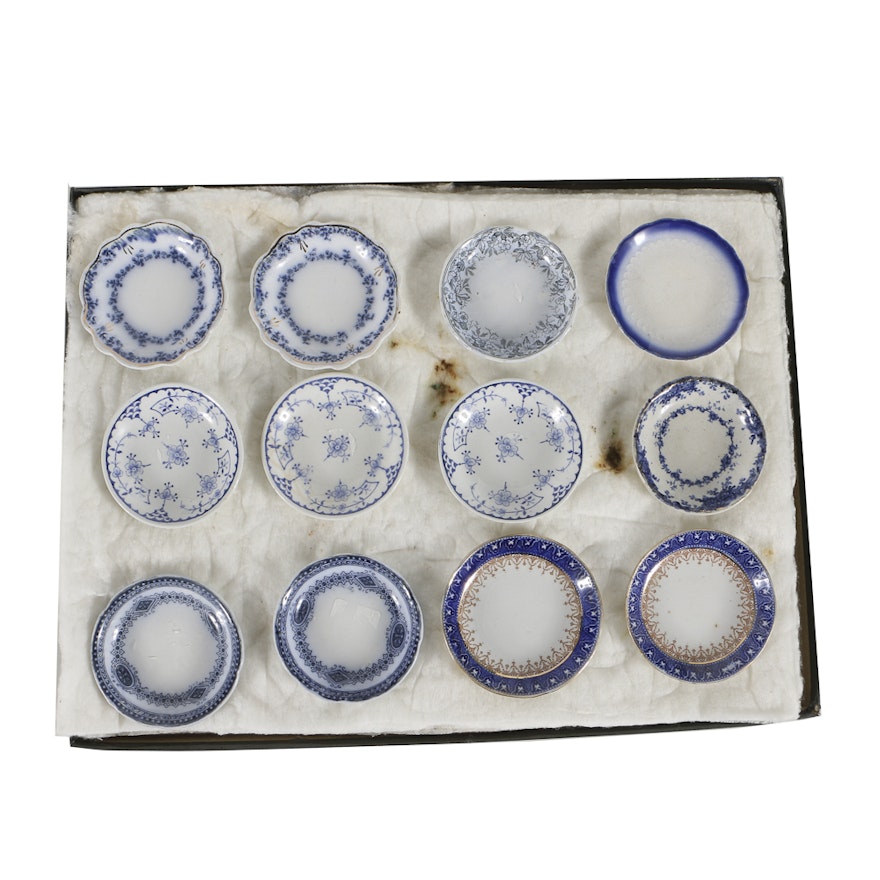 Twelve Porcelain Butter Pats In Glass Top Display Case