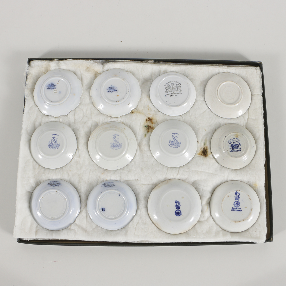 Twelve Porcelain Butter Pats In Glass Top Display Case