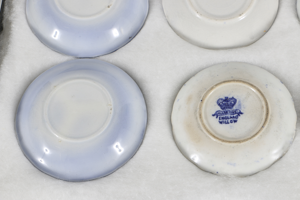 Twelve Porcelain Butter Pats In Glass Top Display Case