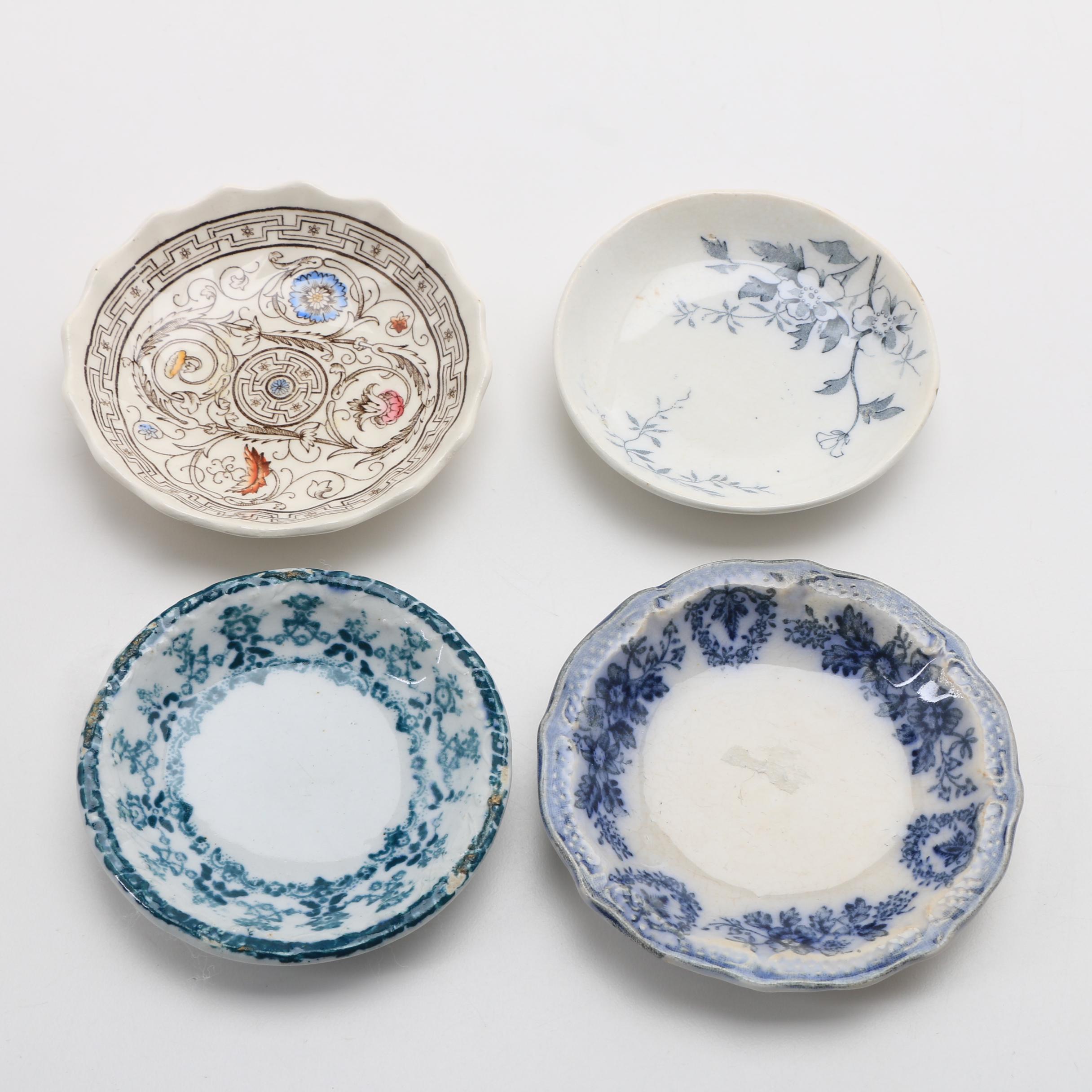 Twelve Porcelain Butter Pats In Glass Top Display Case