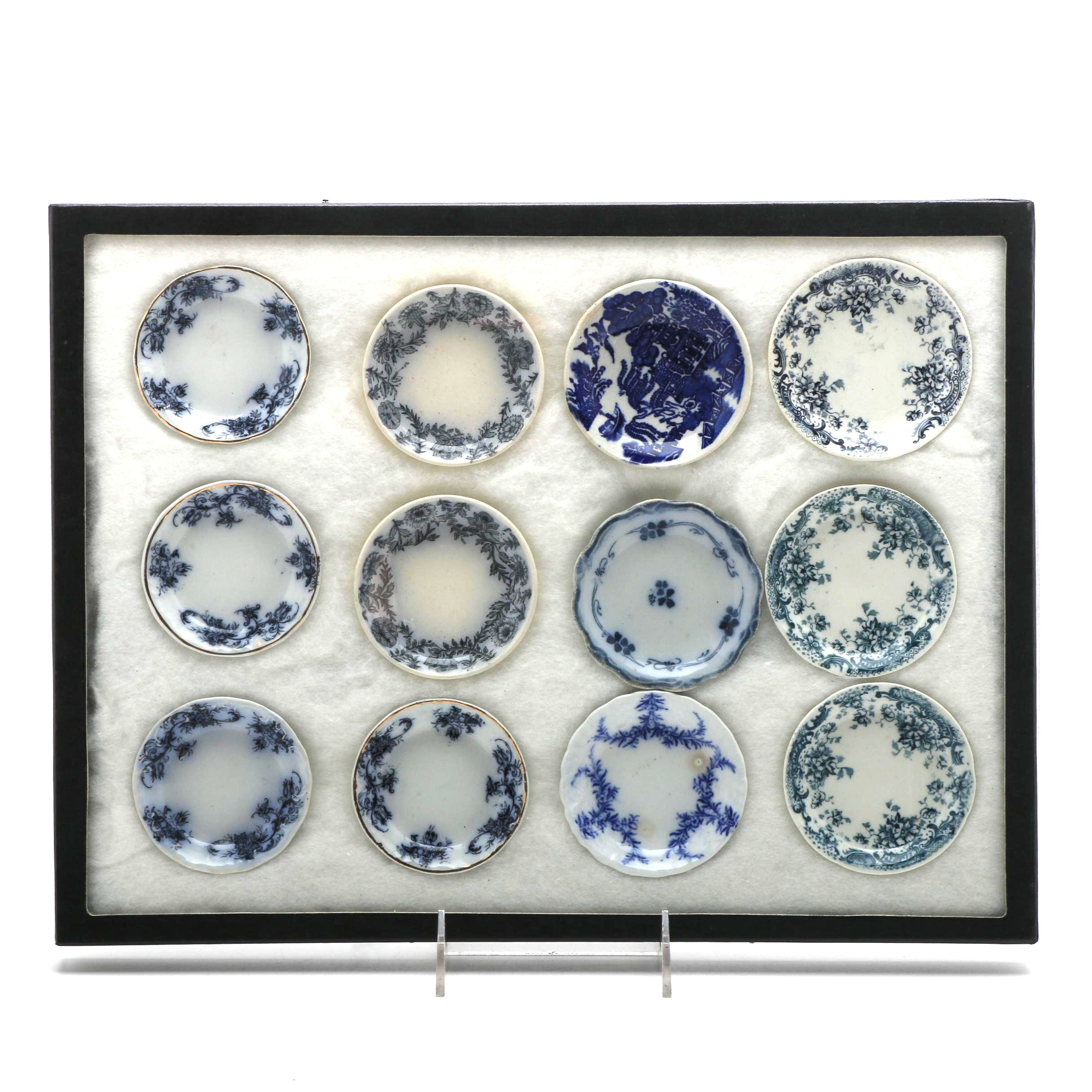 Twelve Porcelain Butter Pats In Glass Top Display Case