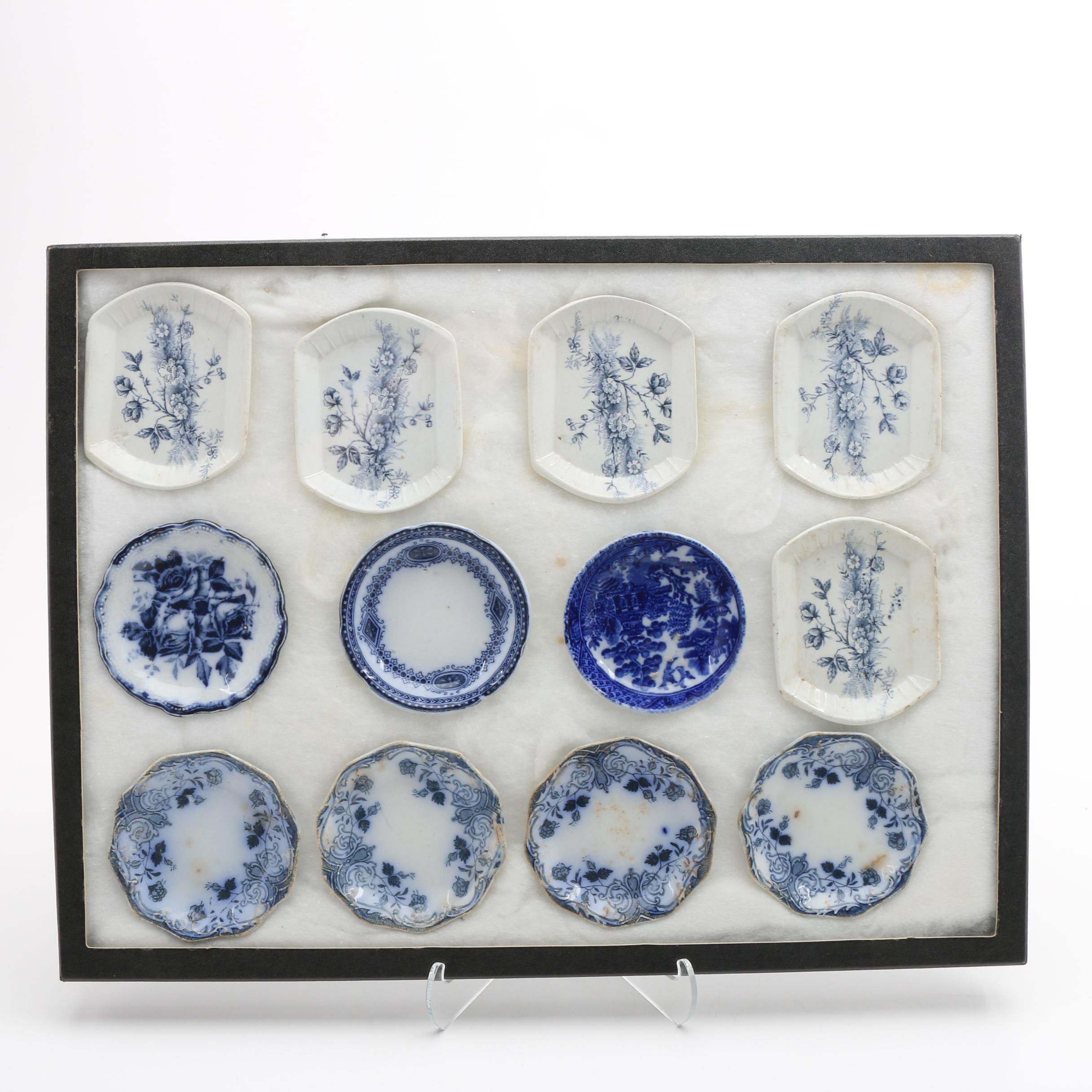Twelve Porcelain Butter Pats In Glass Top Display Case