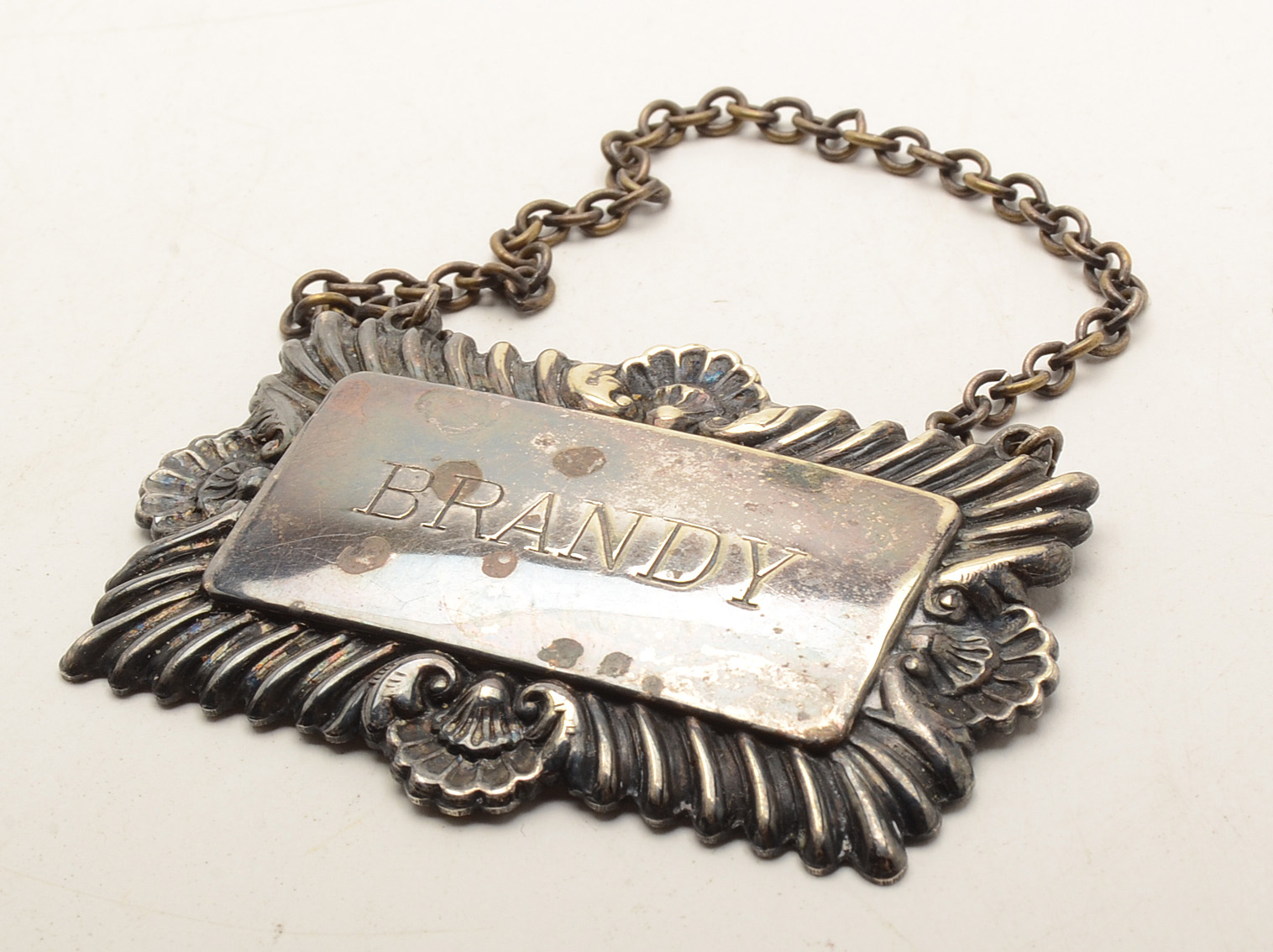 Set of Four Silverplated Coasters with a Brandy Decanter Tag