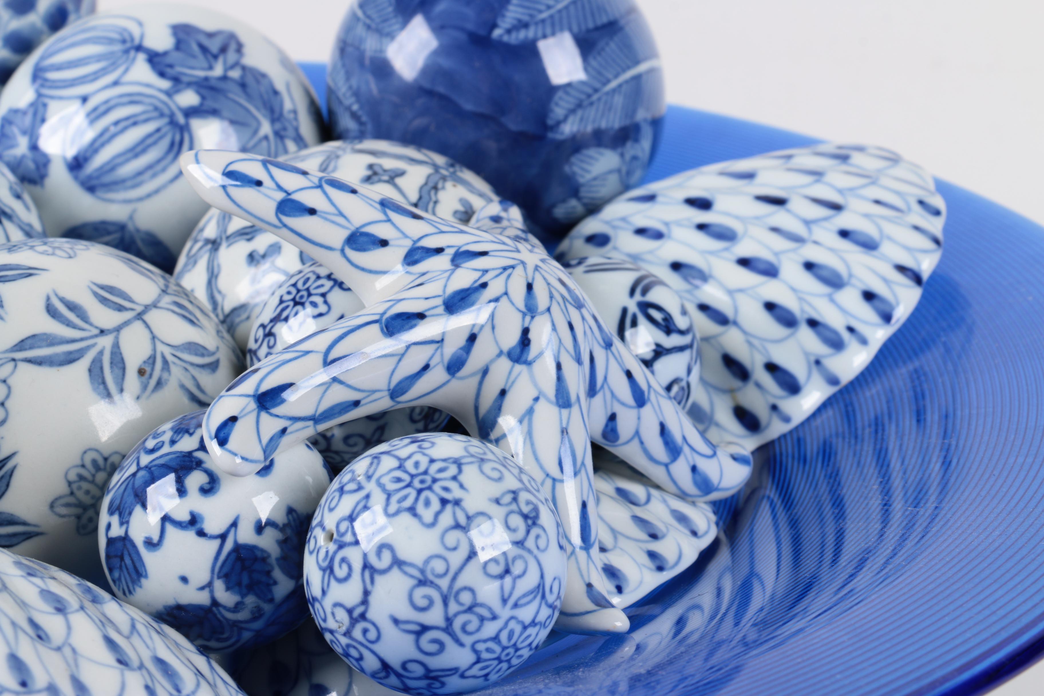 Assortment of Blue and White Ceramic Decor in Blue Glass Bowl