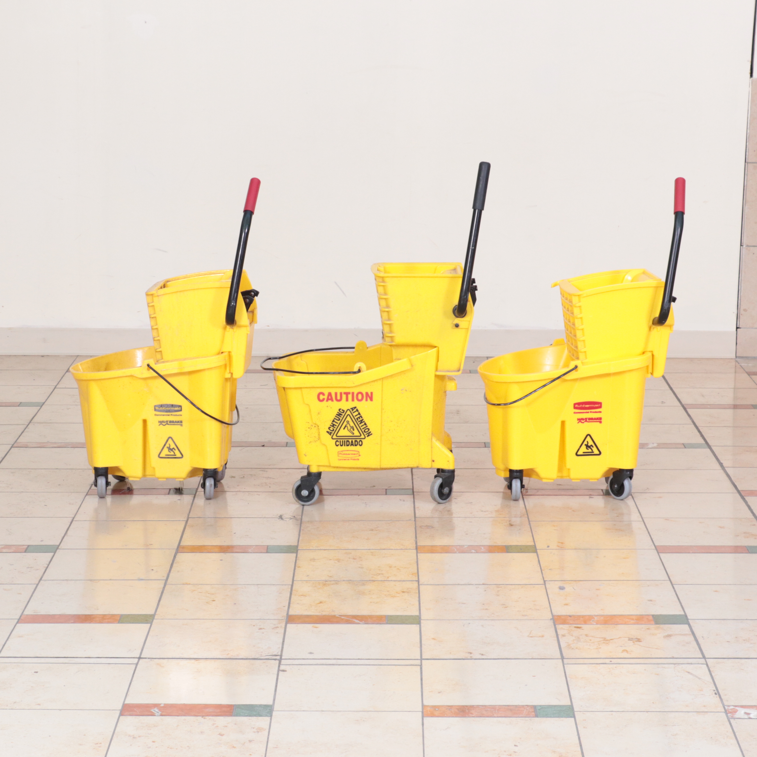 Six Rubbermaid Industrial Wheeled Mop Buckets With Three "Caution" Signs