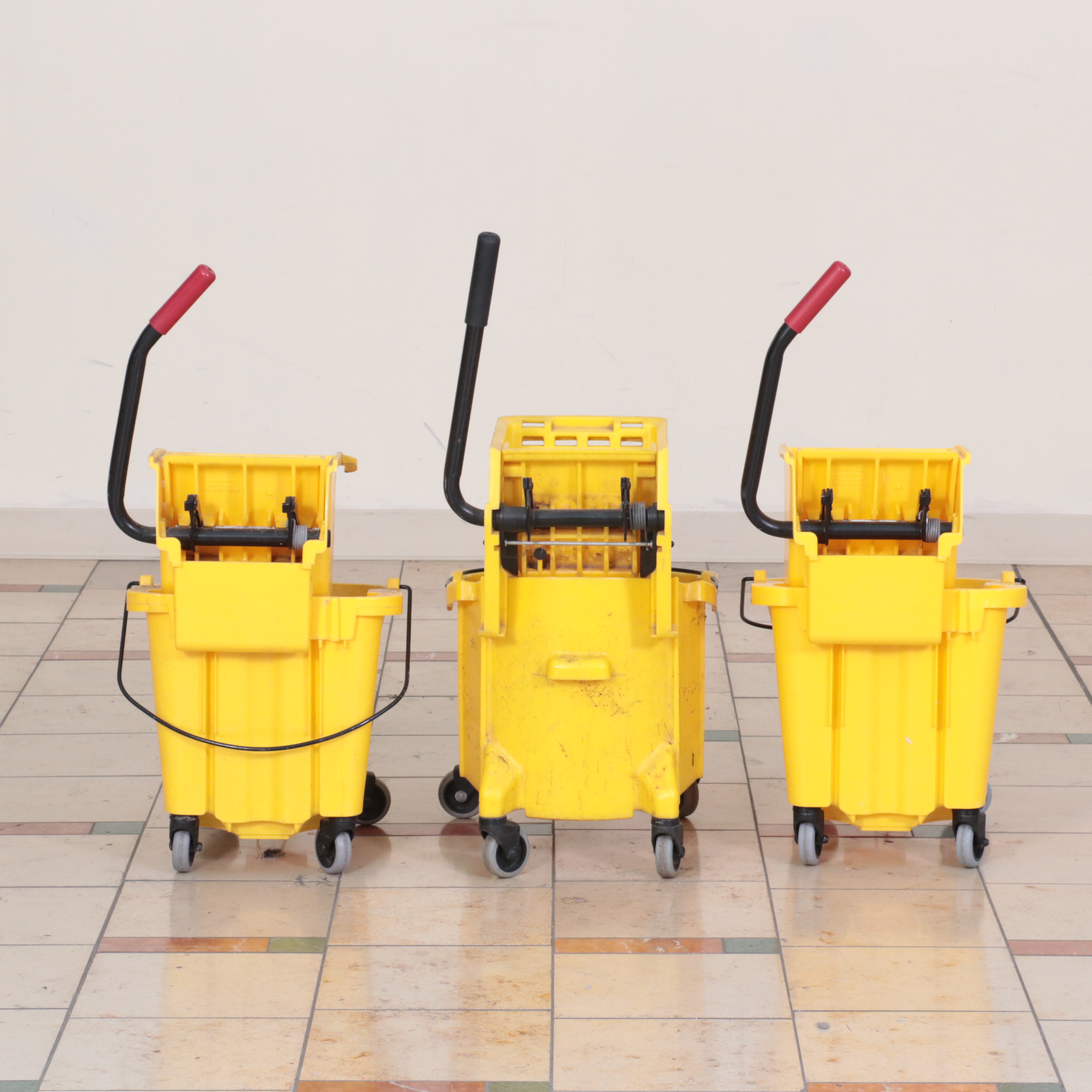 Six Rubbermaid Industrial Wheeled Mop Buckets With Three "Caution" Signs
