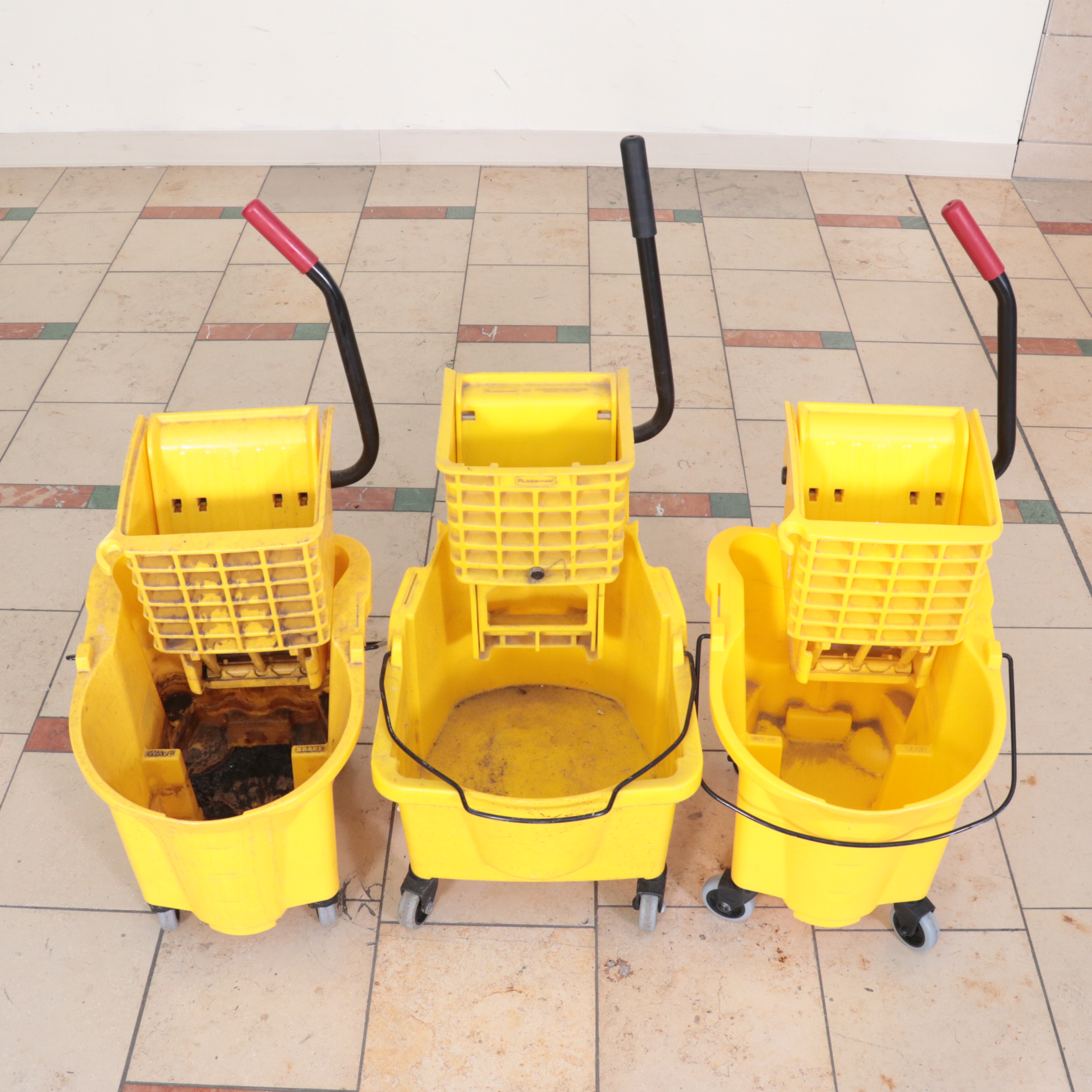 Six Rubbermaid Industrial Wheeled Mop Buckets With Three "Caution" Signs