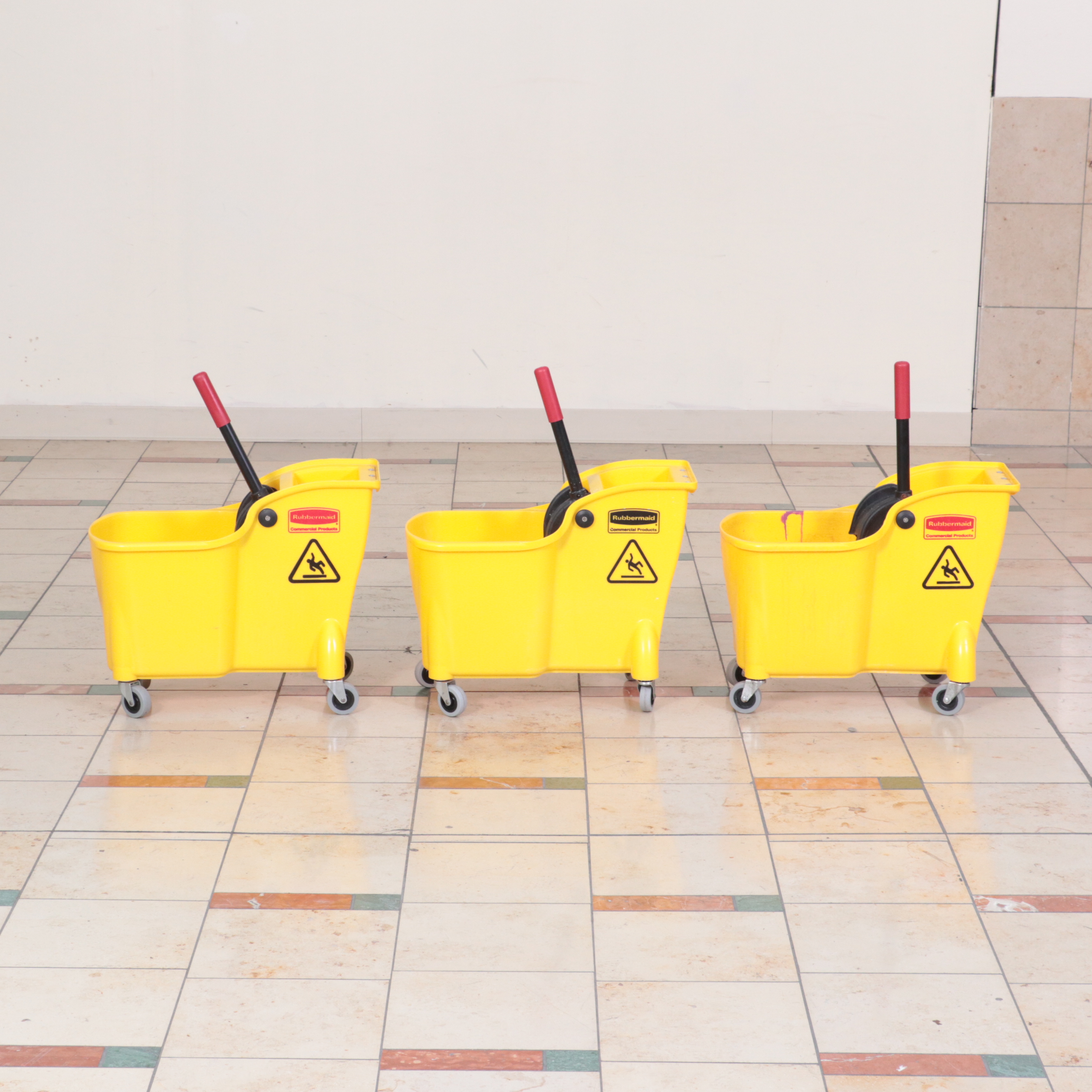 Six Rubbermaid Industrial Wheeled Mop Buckets With Three "Caution" Signs