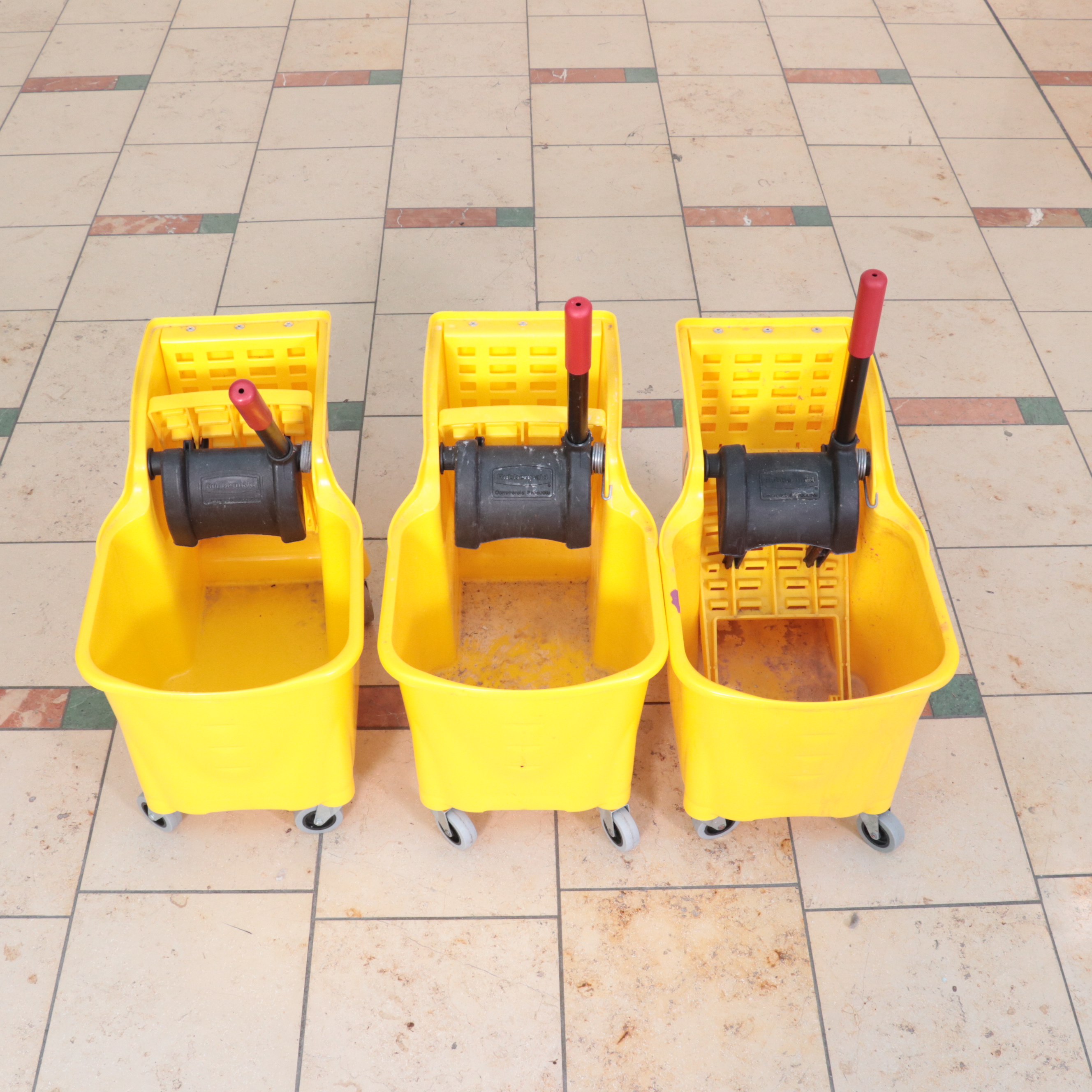 Six Rubbermaid Industrial Wheeled Mop Buckets With Three "Caution" Signs