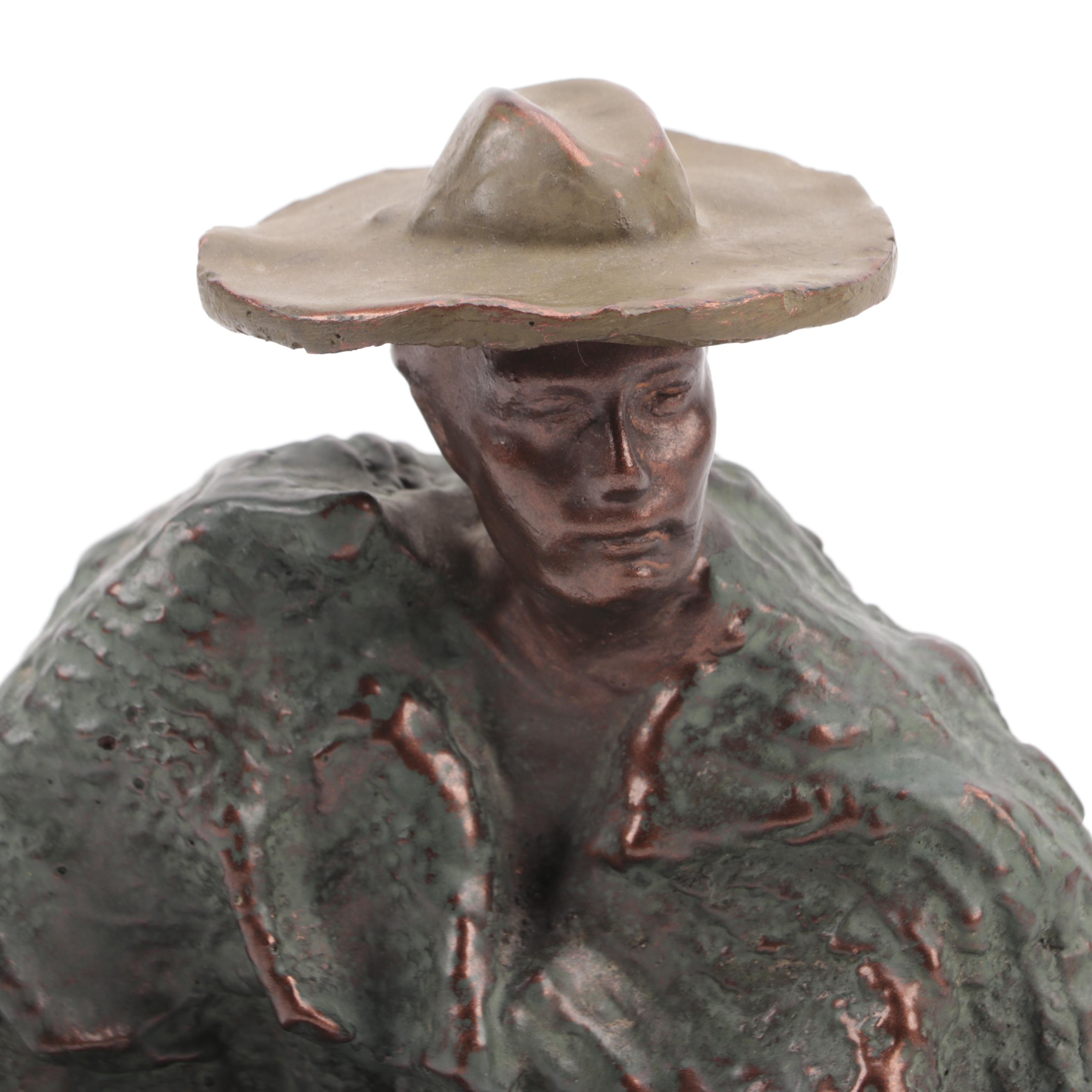 Cast Metal Sculpture of a Seated Man With Hat