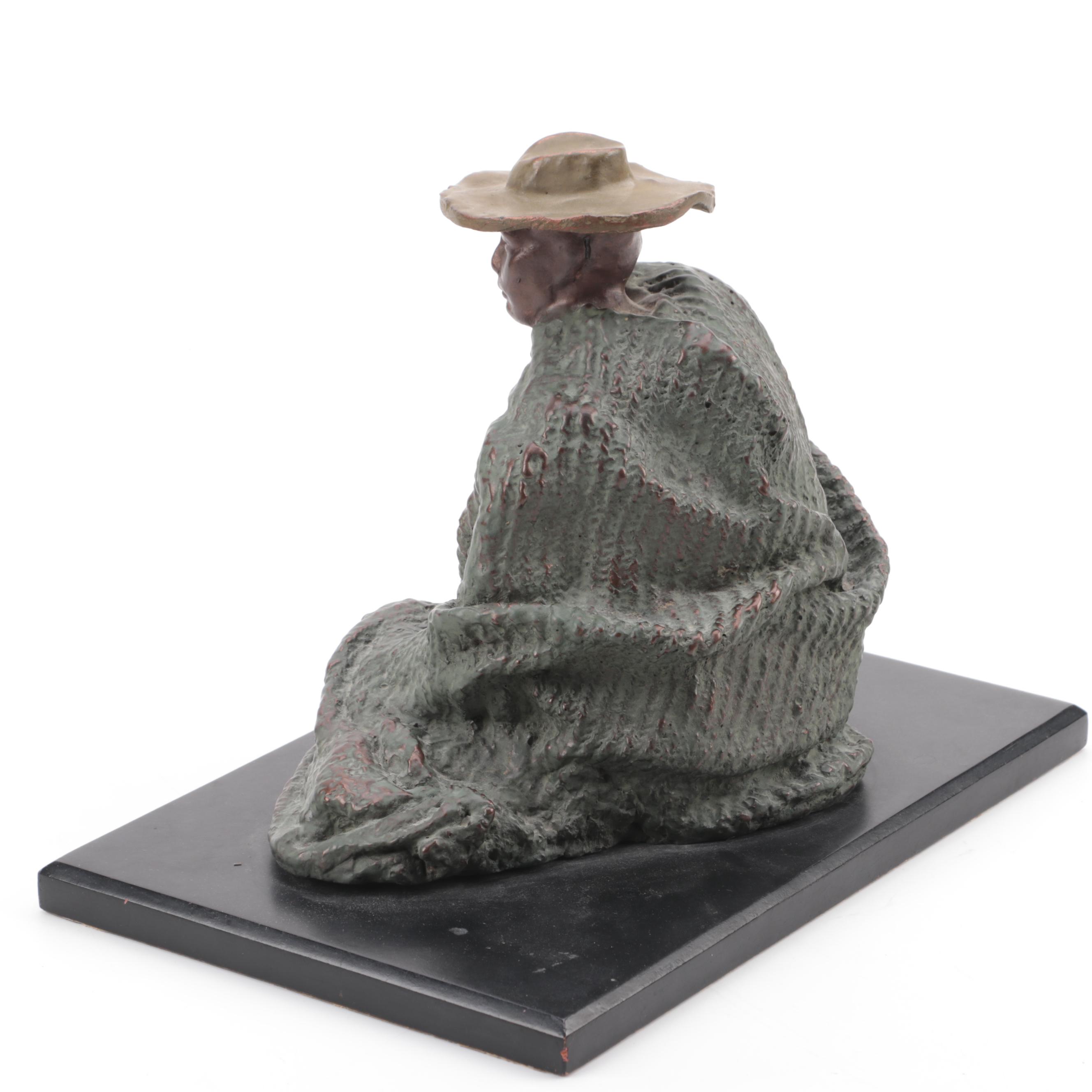 Cast Metal Sculpture of a Seated Man With Hat
