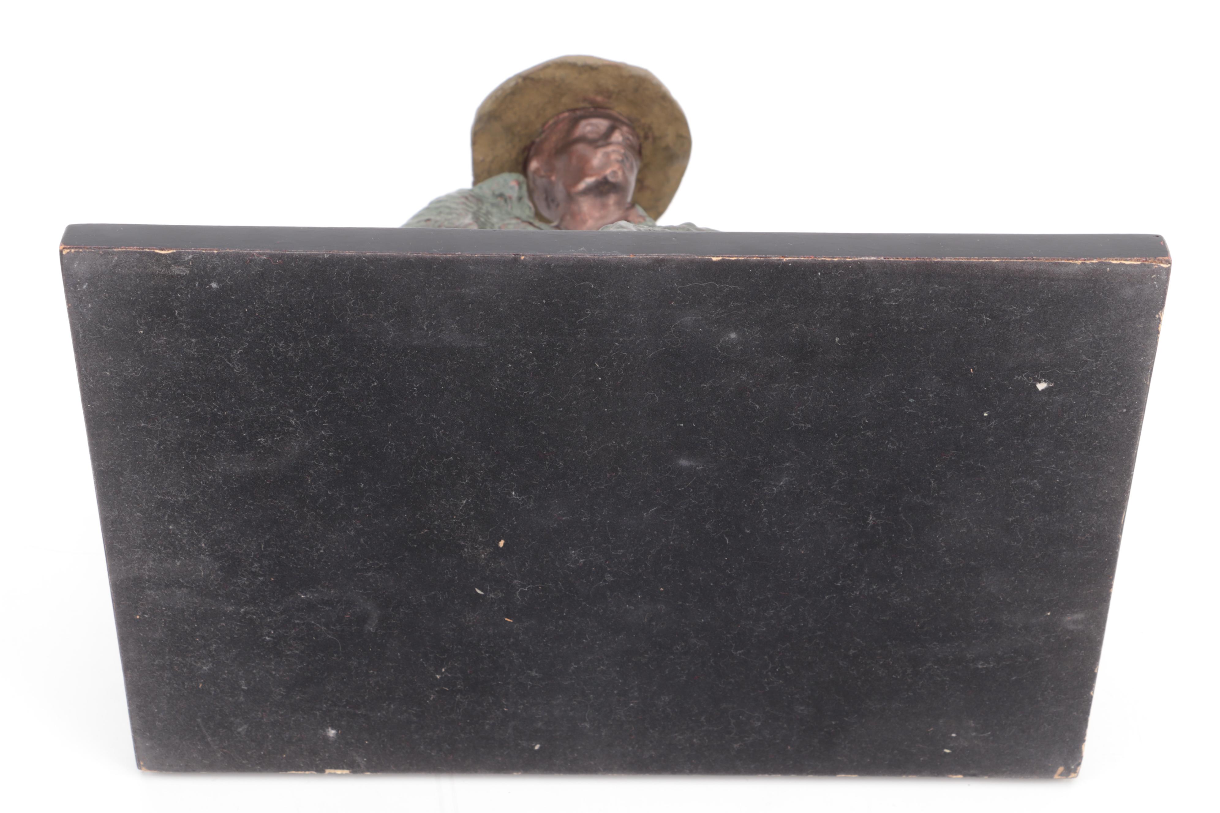 Cast Metal Sculpture of a Seated Man With Hat