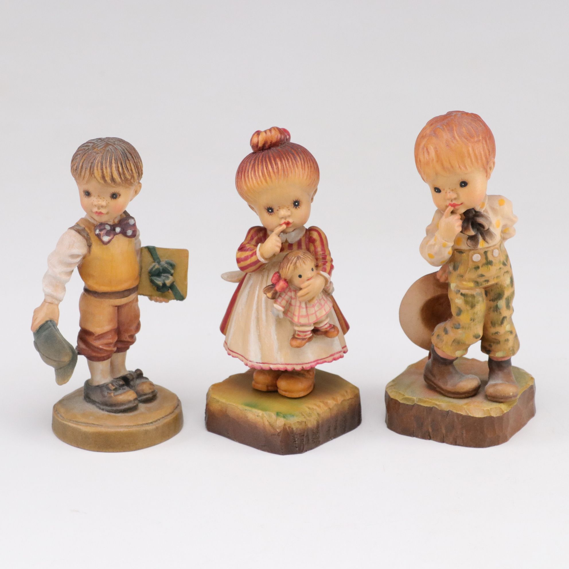 Eleven ANRI Painted Carved Wood Figurines of Children with Two Display Stands