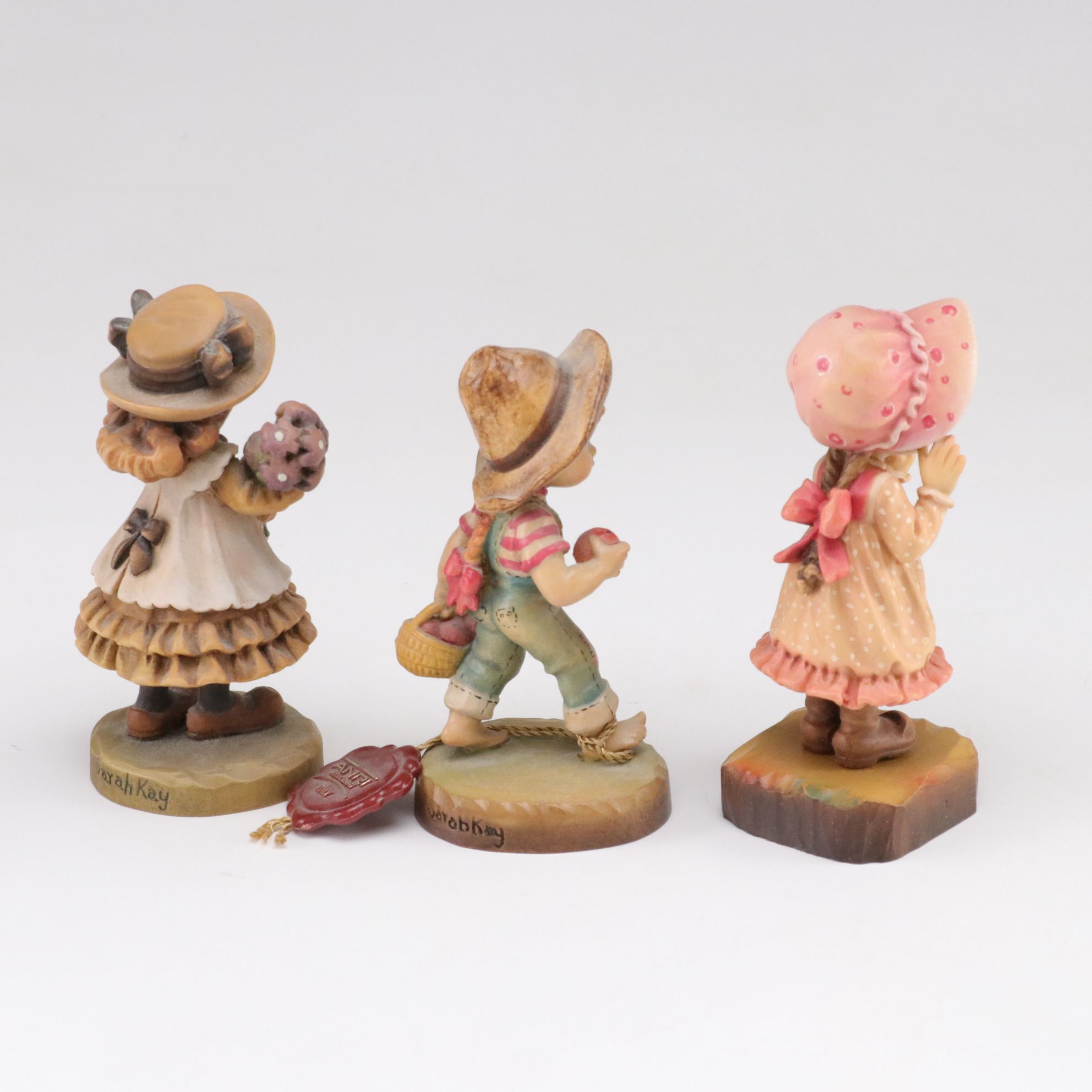 Eleven ANRI Painted Carved Wood Figurines of Children with Two Display Stands