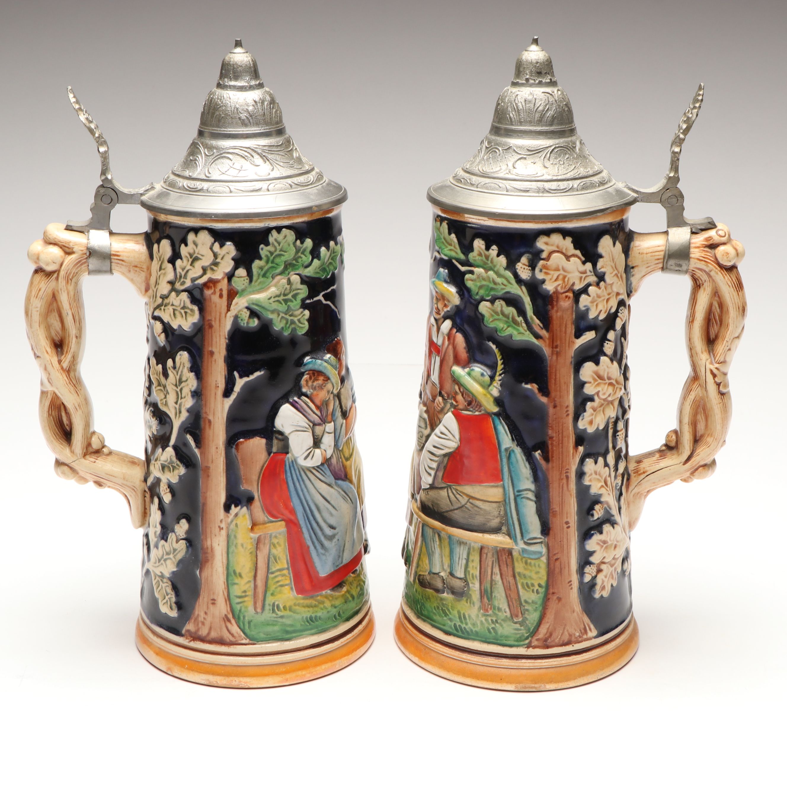 Pair of German Embossed Provincial Scene Steins